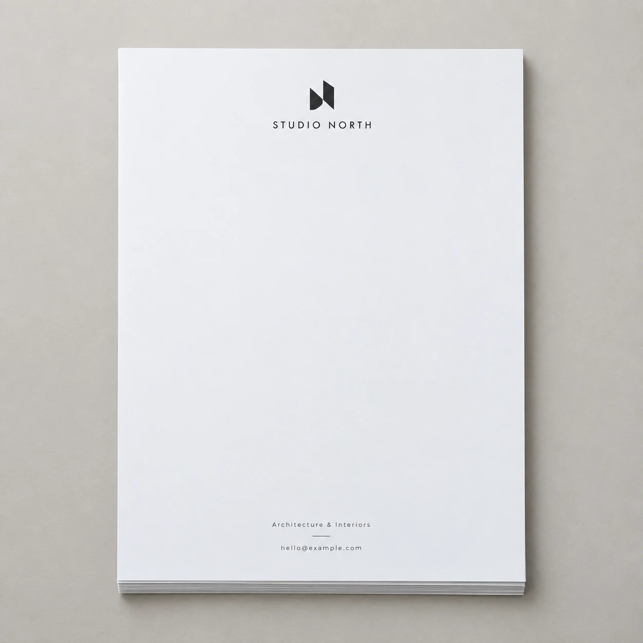 Printed architecture-studio letterhead with a small header and footer photographed on a light studio surface